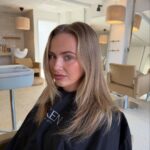 Woman with long honey-blonde hair seated in a bright hair salon