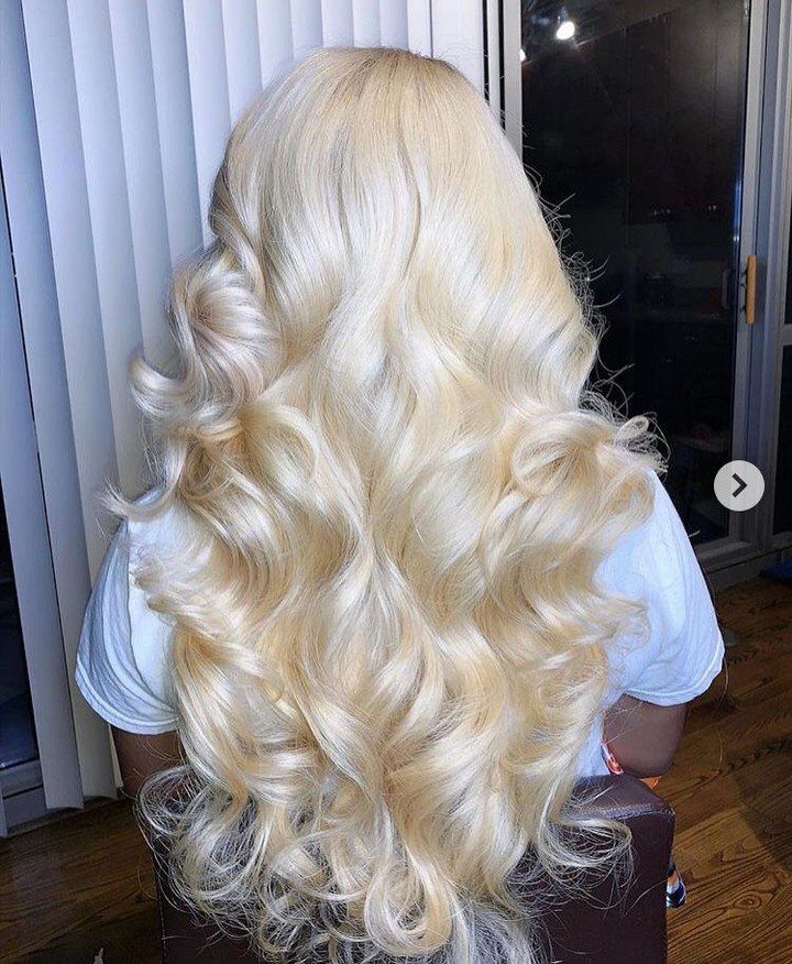 Long platinum blonde curls cascading down the back of a seated person