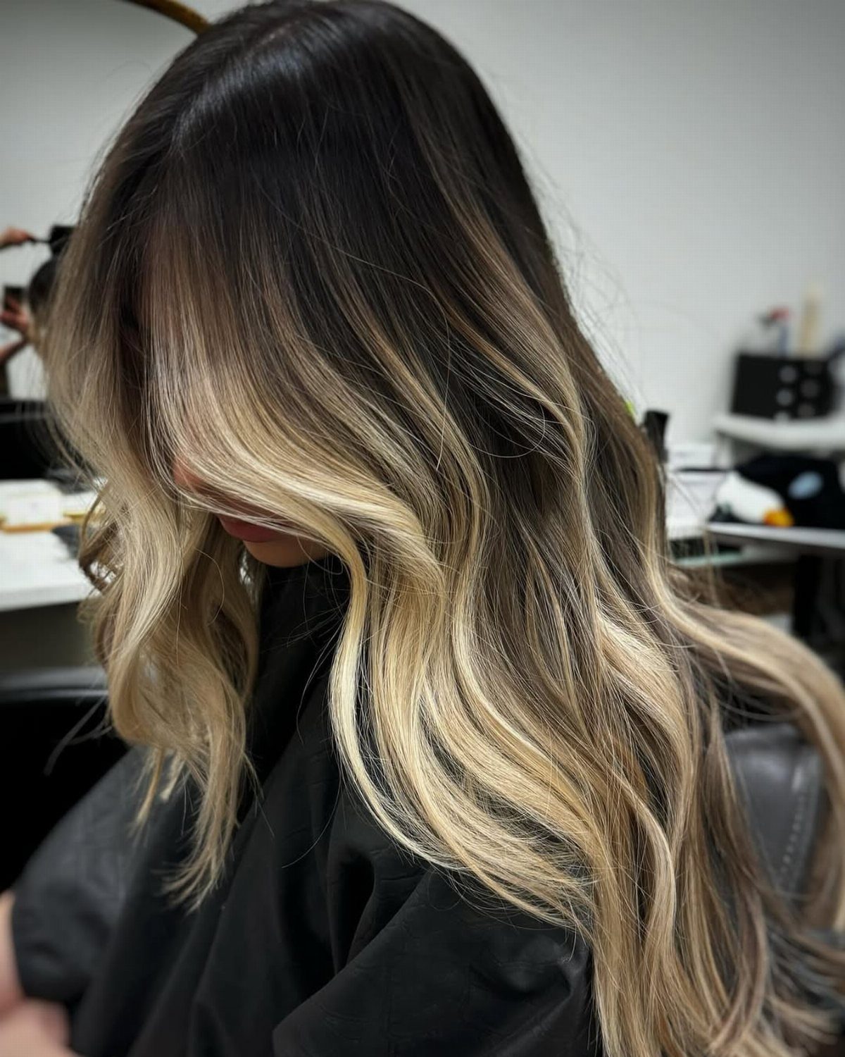 Wavy blonde hair with dark roots blending into bright platinum lengths