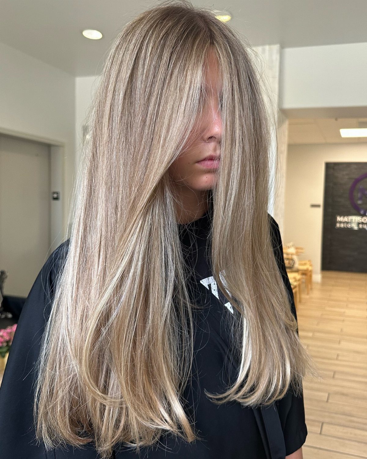 Long sandy blonde hair with lighter highlights styled straight in a salon