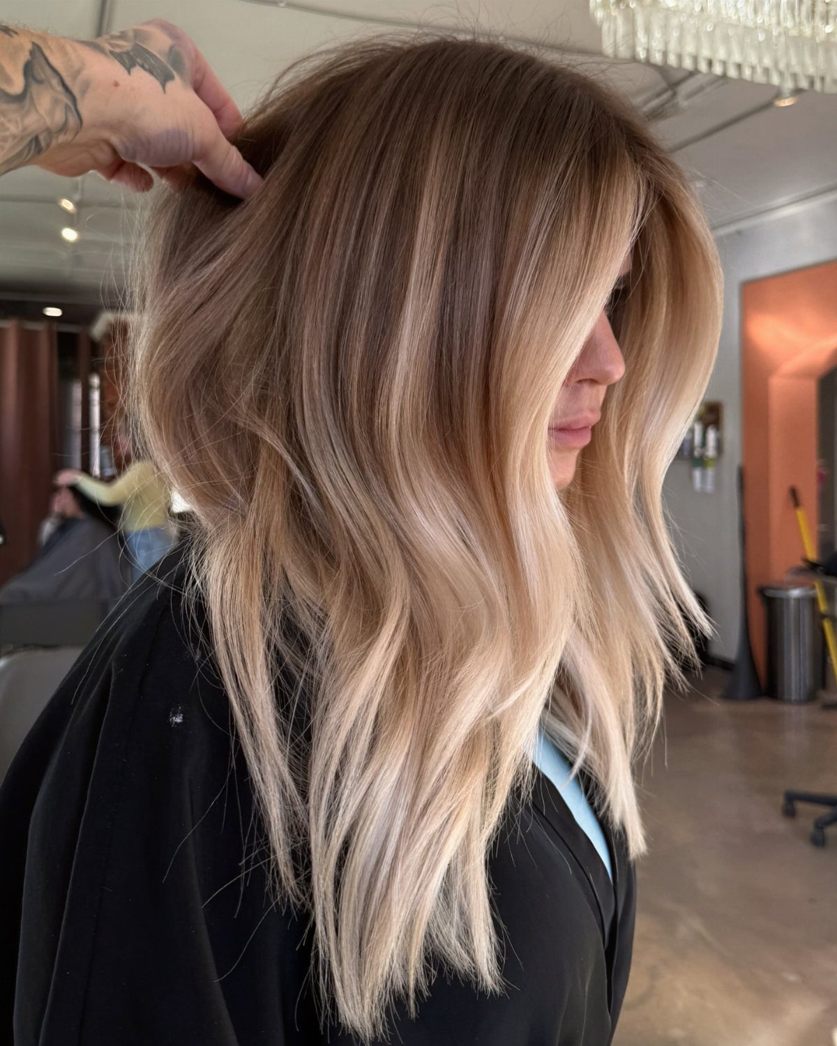 Long blonde hair with golden caramel balayage and darker roots in a salon